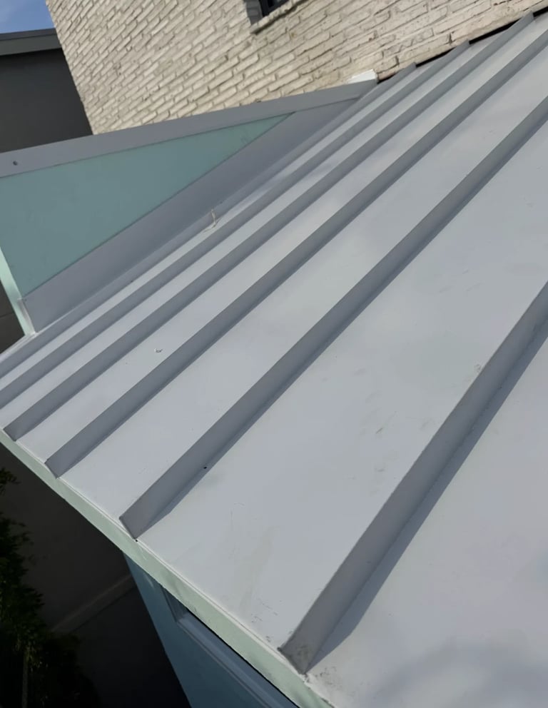 Metal roof with gray and white striped corrugated panels against a brick building wall