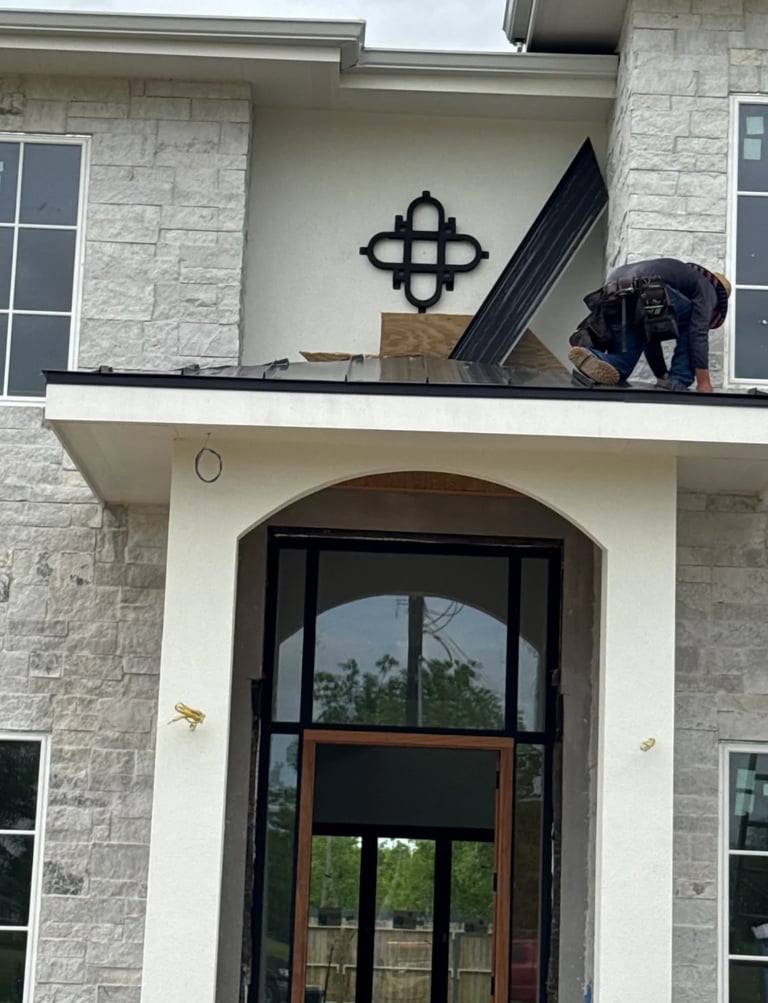 Worker on a roofed balcony installing materials on a modern stone house with a black geometric cross ornament