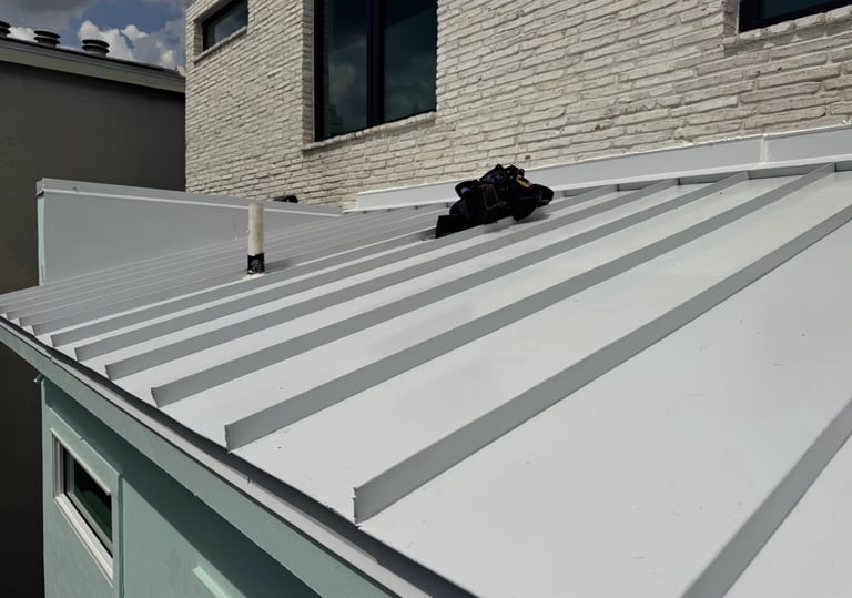 Modern flat roof with gray and white striped metal panels and safety equipment on brick building exterior.