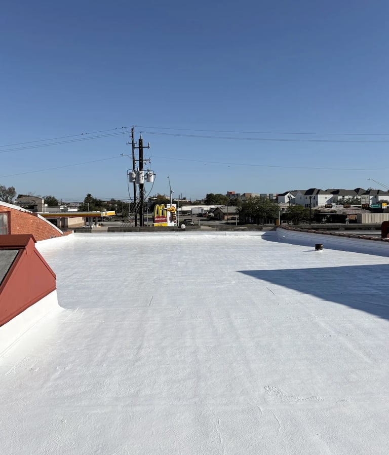 White rooftop with communication tower in background, clear blue sky, industrial area with buildings and residential homes visible