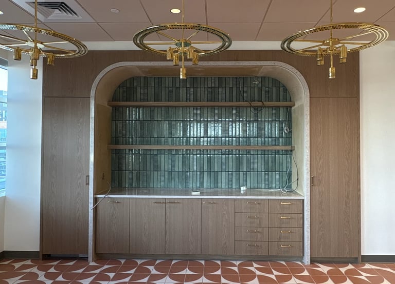 Built-in cabinetry with glass doors and lower storage in a modern interior, featuring brass circular ceiling fixtures and geometric floor pattern.