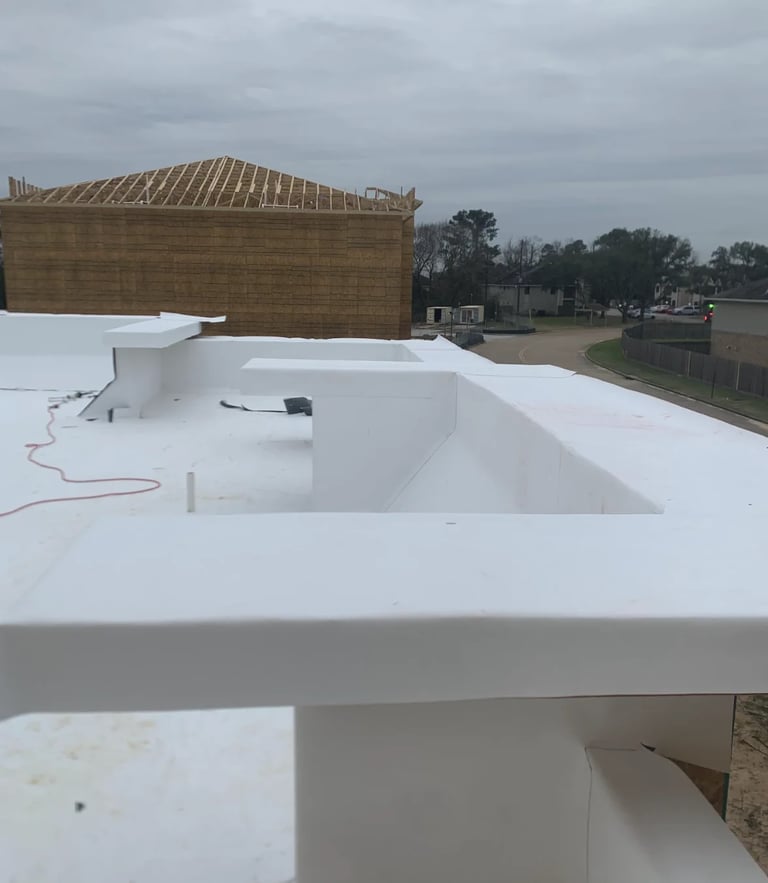 Construction site showing white roof membrane with opening next to wooden framed building under construction