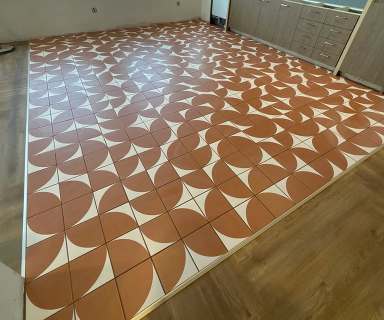 Kitchen floor with geometric tile pattern in brown and white curved designs, wooden cabinets in background