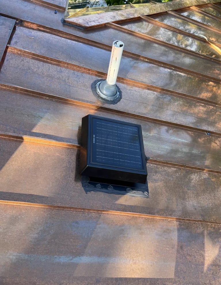 Solar powered roof vent with white duct and black solar panel mounted on metal corrugated roof